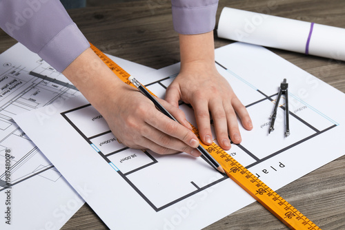 Tableau sur toile Woman with pencil and ruler working on project at wooden table, closeup