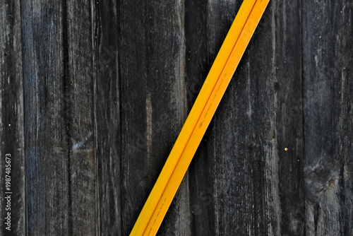 New Diagonal yellow plastic guard and old vertical weathered wooden slats. Diagonal lines create movement or tension, whereas vertical lines often convey stability and strength 