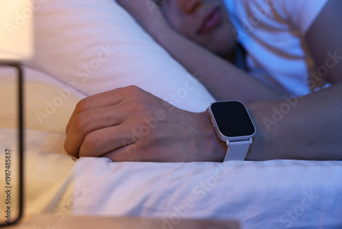 Cuadro en lienzo Young man with sleep tracker sleeping on bed at home, closeup