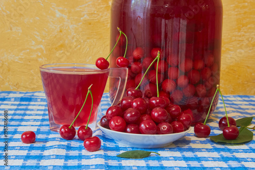 Homemade sour cherry compote in a glass jar with fresh cherries, canned cherry compote and freshly picked cherries