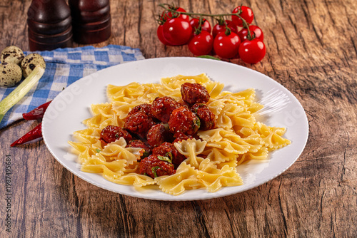 Valokuva Farfalle pasta with meatballs and vibrant garnishes on rustic wooden table