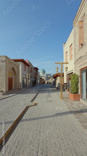 Empty old city street in Tashkent leading to mosque with blue dome