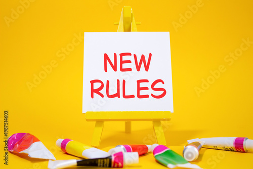 New rules symbol. Concept word Manage stress on wooden blocks. Beautiful yellow background with paints and easel. Business and New rules concept. Copy space