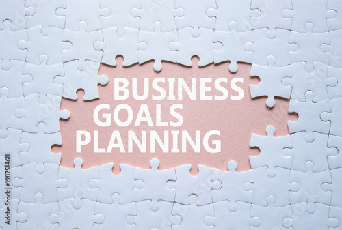 Business Goals Planning symbol. White puzzle with words Business Goals Planning. Beautiful pink background. Business concept. Copy space.