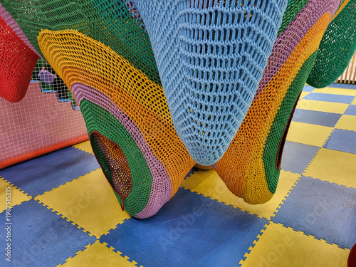 The hanging part is a colorful knitted play maze in the children's room of a supermarket