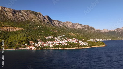 Aerial view of Drasnice village on the Makarska Riviera in Croatia, featuring traditional houses with red roofs nestled between the Biokovo mountains and the blue Adriatic Sea