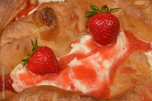 Close up view of a traditional Karpatka cake made of choux pastry with creamy filling and fresh red strawberries with sweet syrup