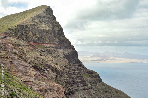 Quadro su tela Steep volcanic mountain cliff with visible sedimentary layers overlooking the ocean in Lanzarote