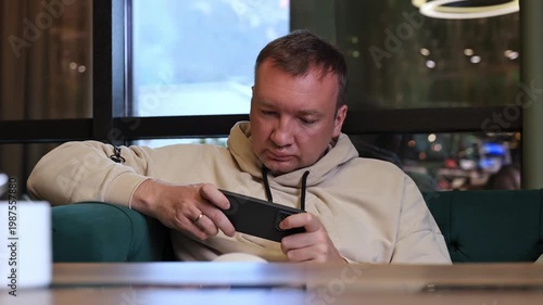 A man plays a game on a smartphone.