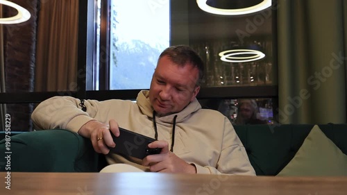 A man plays a game on a smartphone.