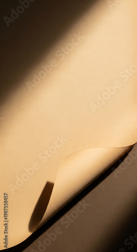 Blank beige paper sheet with curled corner mockup. Minimalist aesthetic background with dramatic diagonal shadow and warm sunlight. Vertical template for stationery, flyer or poster design.