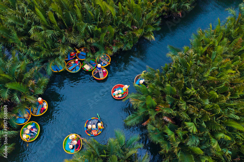 Bild auf Leinwand Asian adults enjoying round boat ride through lush greenery in hoi an, vietnam