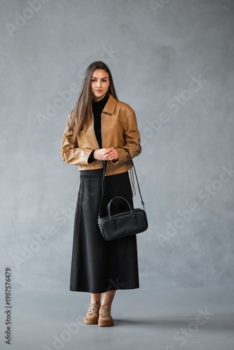 Wallpaper Mural Caucasian Woman Standing Side Profile Wearing Brown Jacket And Black Skirt, Holding Black Leather Handbag Torontodigital.ca