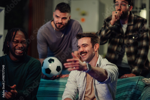 Tableau sur toile Diverse friends enjoying soccer game on television at home, cheering and laughin
