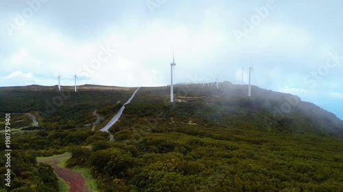 A winding road through the misty, wind-swept Paul da Serra plateau in Madeira, dotted with renewable energy turbines. An atmospheric drive.