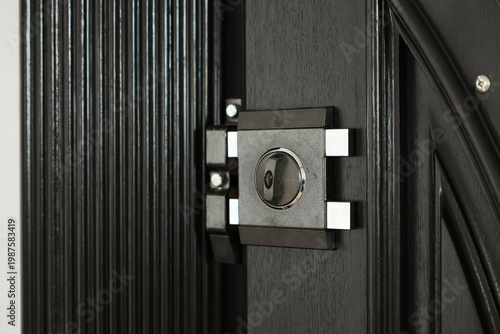 Fotografie Close-up view of a metal door lock and deadbolt mounted on a dark wood entrance door, conveying security, safety, protection and durable hardware for homes, apartments and commercial properties