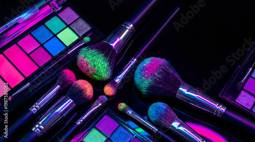 Neon glowing makeup brushes and eyeshadow palettes on black background