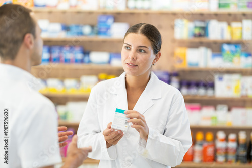 Tableau sur toile Female consultant pharmacist holds box in hands and offers man client to purchase remedy to alleviate condition