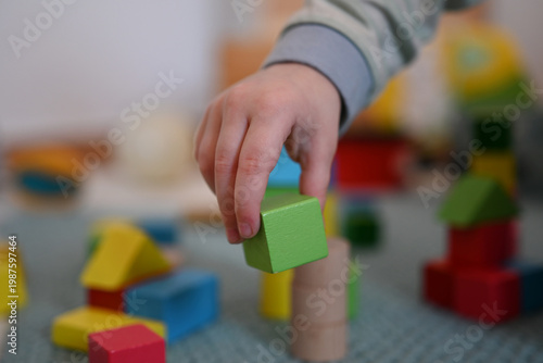 A child’s hand holding a block and is playing with blocks