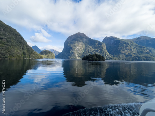 Obraz na płótnie Reflections of the towering mountains and cliffs at Doubtful Sound on a blue sky