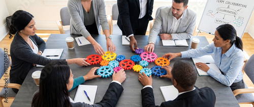 Diverse business team assembling colorful interlocking gears together on conference table during workshop