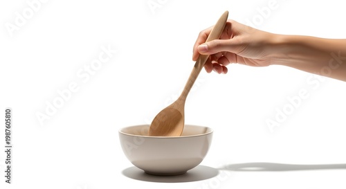 Minimal Cooking Scene with Hand Holding Wooden Spoon Above Small Bowl on White Background