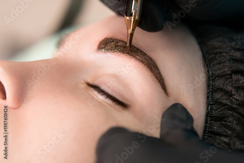 Permanent tattoo makeup procedure. Eyebrow tattoo make-up. Brow tattoo. Close up, selective focus