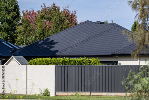 Schilderij op canvas Modern Australian residential house featuring a dark corrugated metal roof and matching metal slat fence