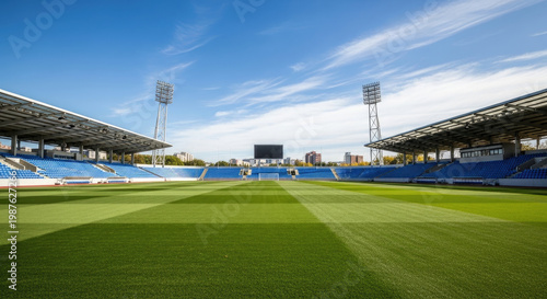 Expansive view of a vibrant green soccer field in a stadium under a bright blue sky with tall stadium lights; perfect venue