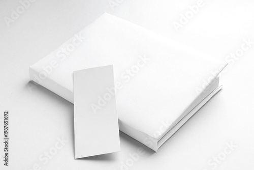 Book with white bookmark on light grey background, closeup. Space for text