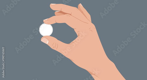 A person's hand delicately holding a small white spherical object between their thumb and forefinger against a neutral background