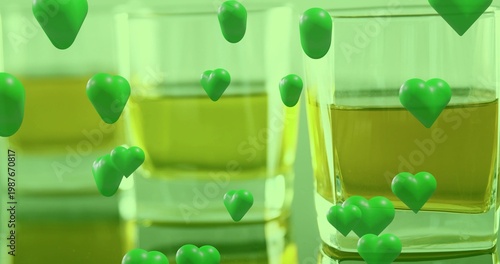 Showing square glass tumbler on reflective table, holding amber liquid and green hearts, copy space