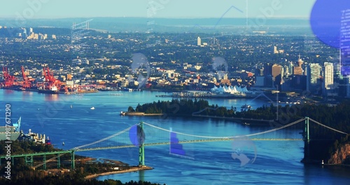 Spanning green suspension bridge crossing wide harbor, red cranes and white sail terminal visible
