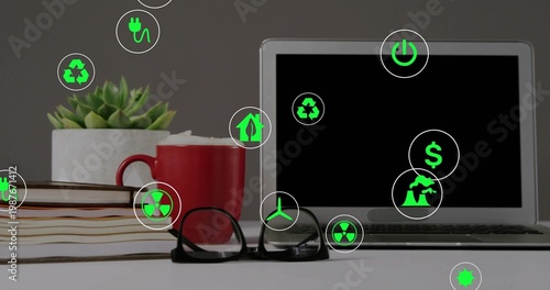 Displaying silver laptop on right of office desk, with books, red mug, green icons, copy space