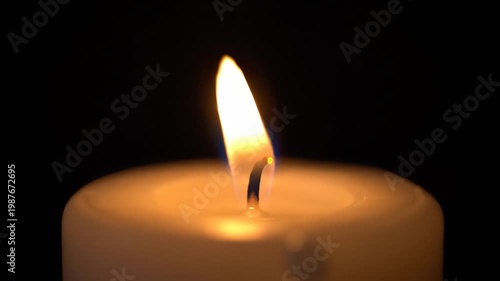 Single candle flame burning against a black background macro shot