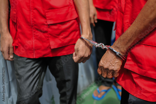 Quadro em tela Two suspects in red vests handcuffed together during a legal investigation or criminal court proceeding