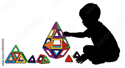 Silhouette of a boy playing with colorful magnetic building tiles