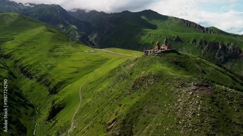 Cinematic 4K ProRes 422 aerial orbit of Gergeti Trinity Church at sunset. Iconic landmark in Kazbegi, Georgia, Caucasus.