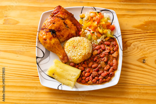 Fotografie Complete Colombian lunch with roasted chicken, beans, rice, boiled yucca, and fresh vegetables