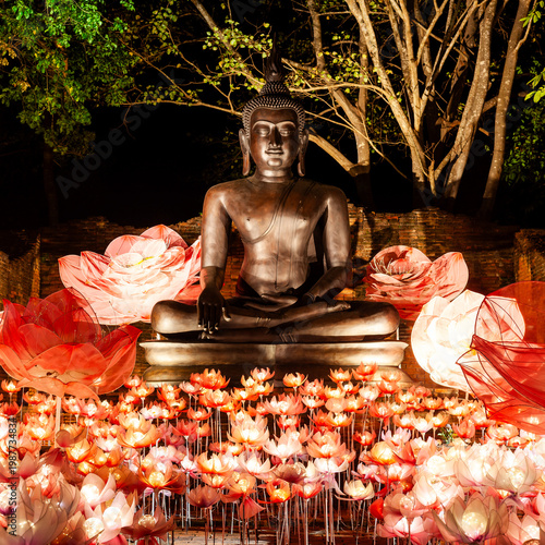 Ratchaburi, Thailand - Dec 17, 2025: Buddha statue. Lotus-shaped lanterns and flowers light the sculpture at night. Nasatta Light Festival takes place in Ratchaburi temple grounds, Thailand.