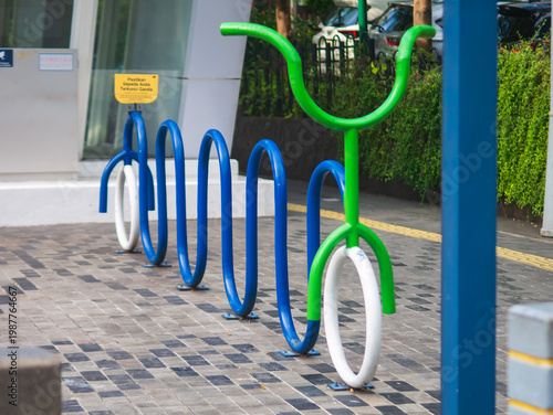 Colorful bicycle rack shaped like playful figures installed on a modern sidewalk, promoting eco-friendly transport and urban cycling infrastructure in a clean city environment.