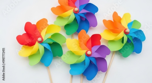 Four colorful paper pinwheels on wooden sticks arranged on clean white surface.
