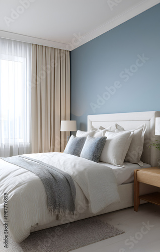 A serene bedroom scene features a made bed with multiple pillows, a light blue wall, and flowing white curtains. The room is softly lit