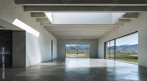 A spacious interior with a polished concrete floor, light streaming in from a skylight and large windows. The windows overlook a scenic landscape