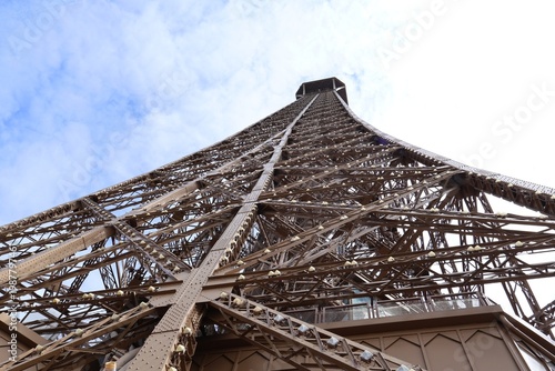 Low-angle view looking up the metal lattice structure of the Eiffel Tower in Paris, France