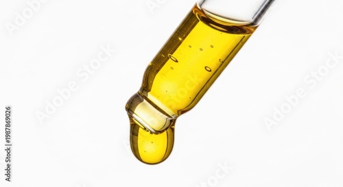 Golden viscous liquid dripping from glass dropper, macro detail