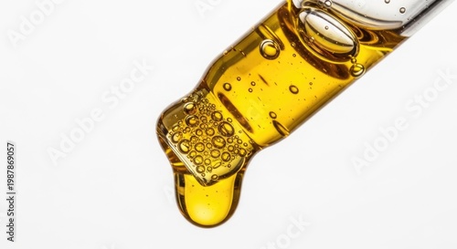 Golden CBD oil drop clinging to a glass dropper in a macro close-up