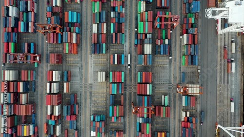 Aerial Top view of a large cargo ship loading and unloading containers at a deep-sea port. This aerial scene highlights global logistics, international trade, and maritime transportation hubs.