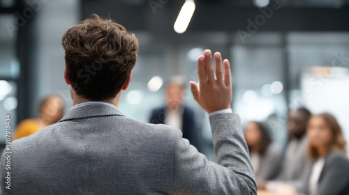 A corporate man raising his hand for attention during a discussion.