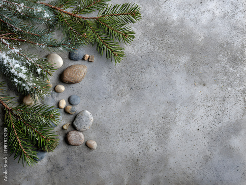 Green pine branches and smooth stones on a gray surface with winter details in a natural setting